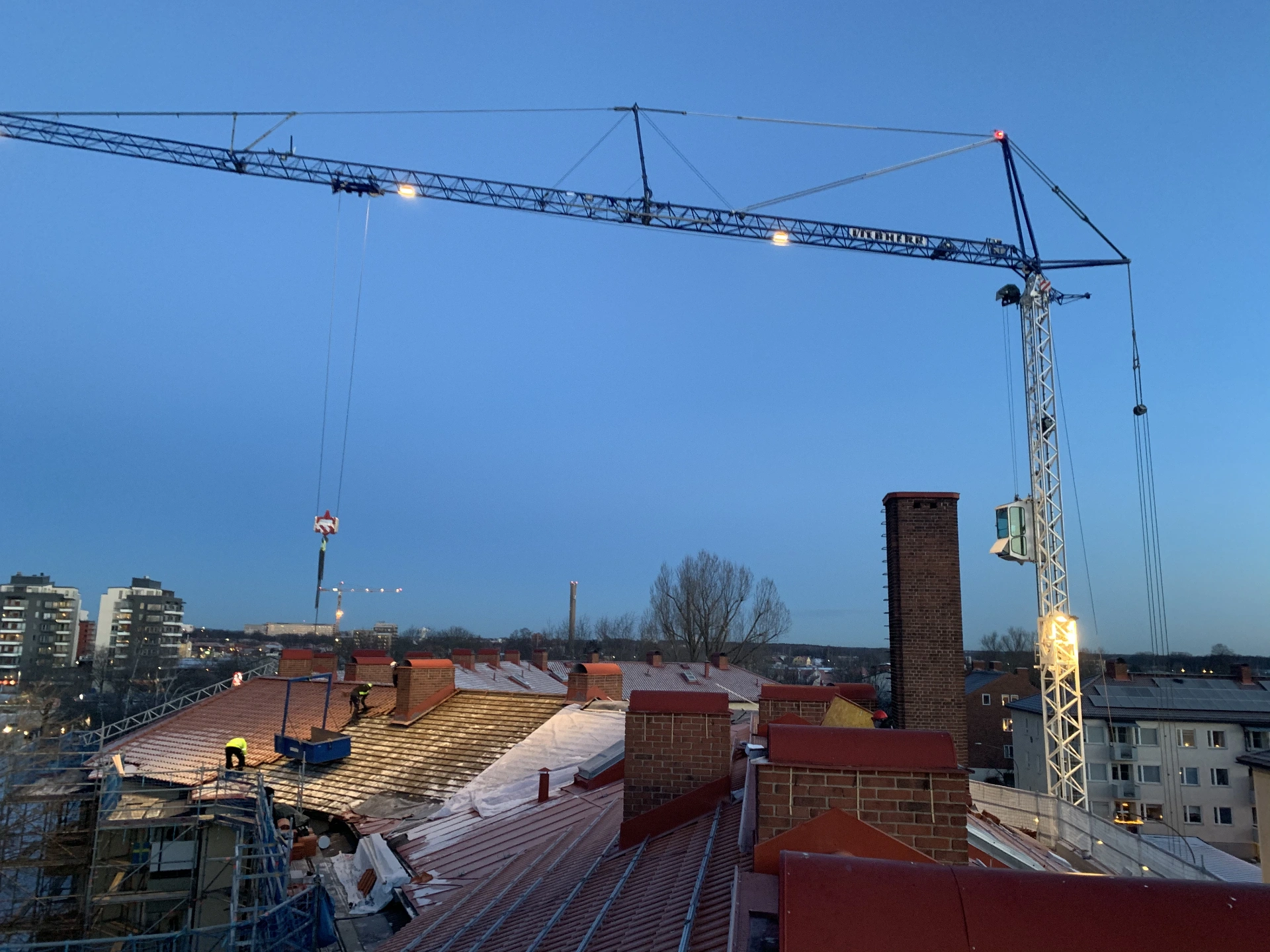 Byggkran över takarbete på flerbostadshus