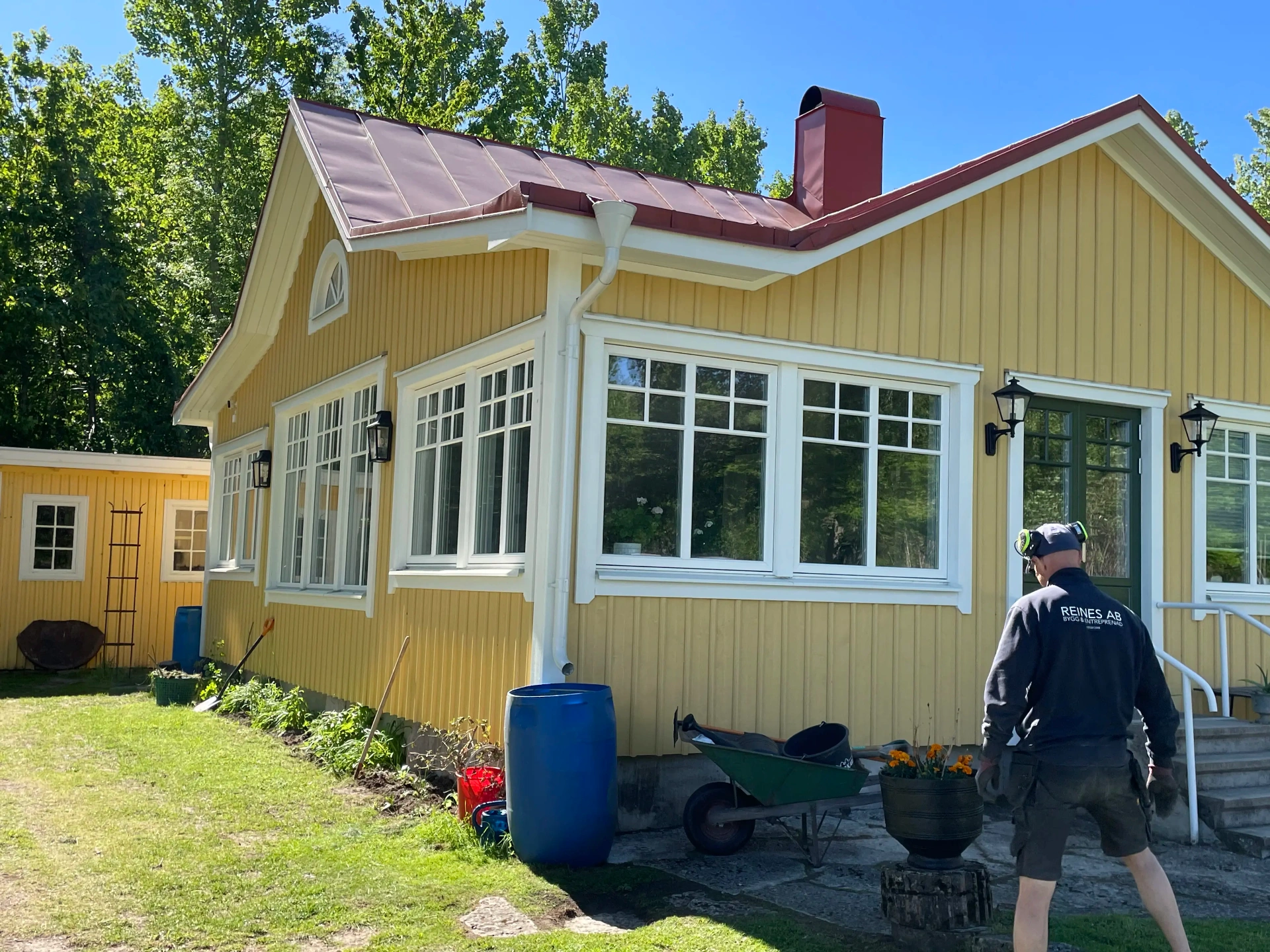 Gult trähus med nya fönster och snickare på tomten