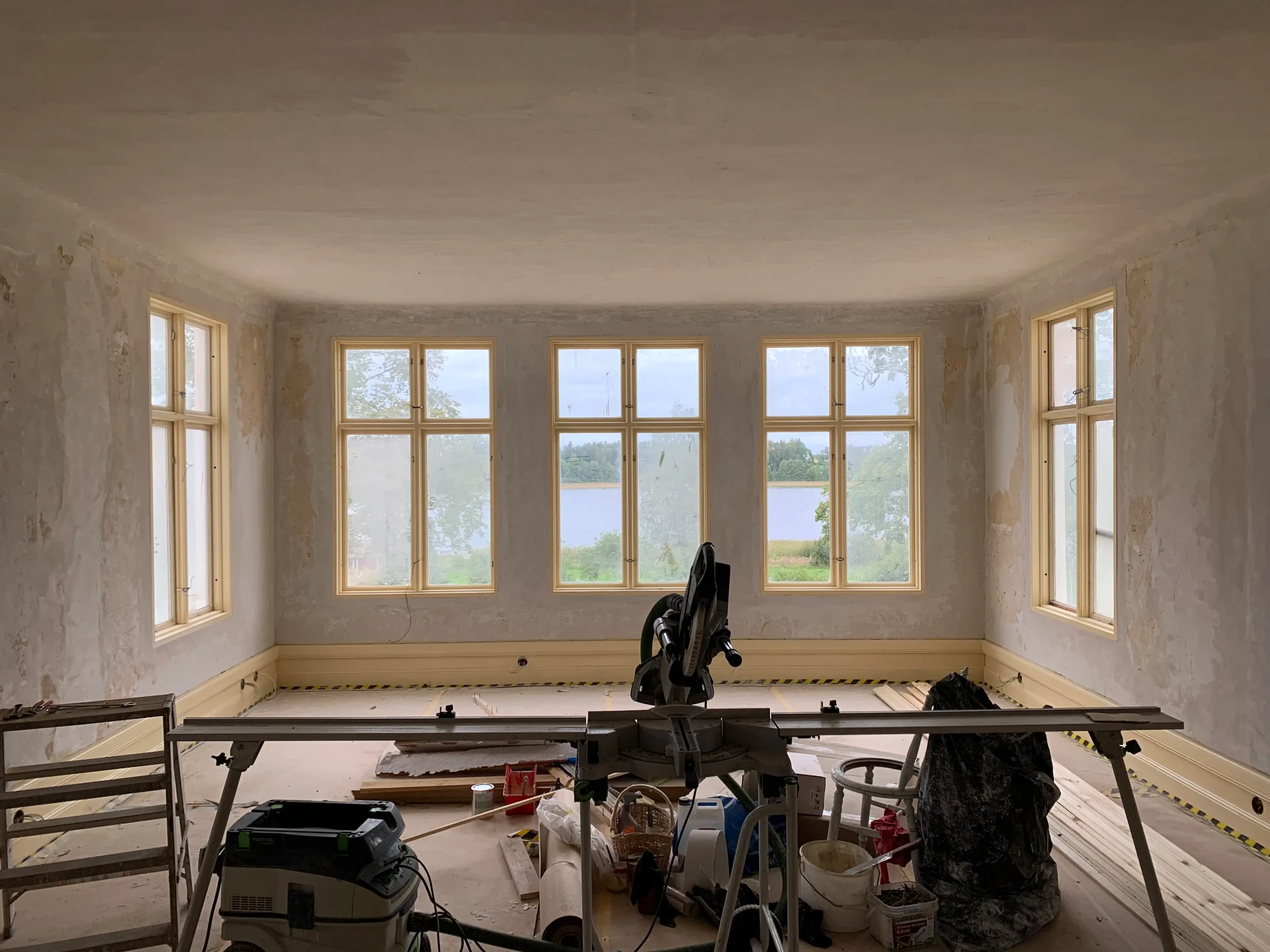 Rum under renovering med spröjsade fönster mot sjön